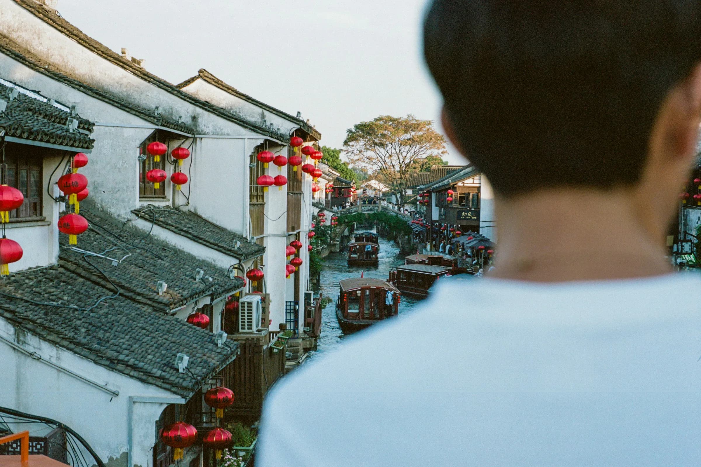 Traveler overlooking lantern-lined canals and whitewashed houses on Suzhou's Pingjiang Road