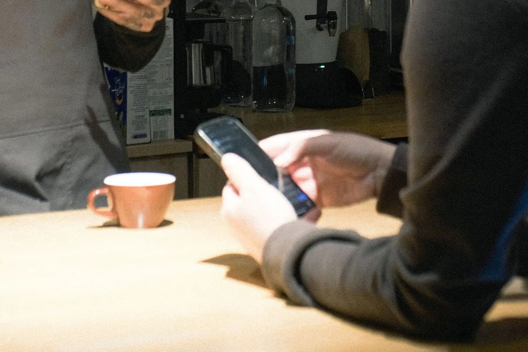 Cafe customer holding a phone during a merchant interaction