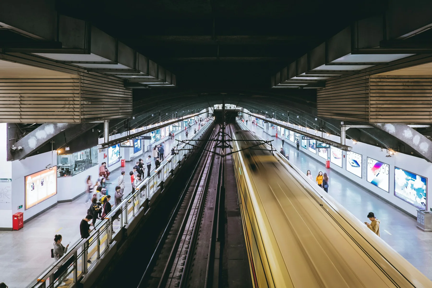 Passengers waiting as a train moves through Guangzhou's Huadiwan metro station