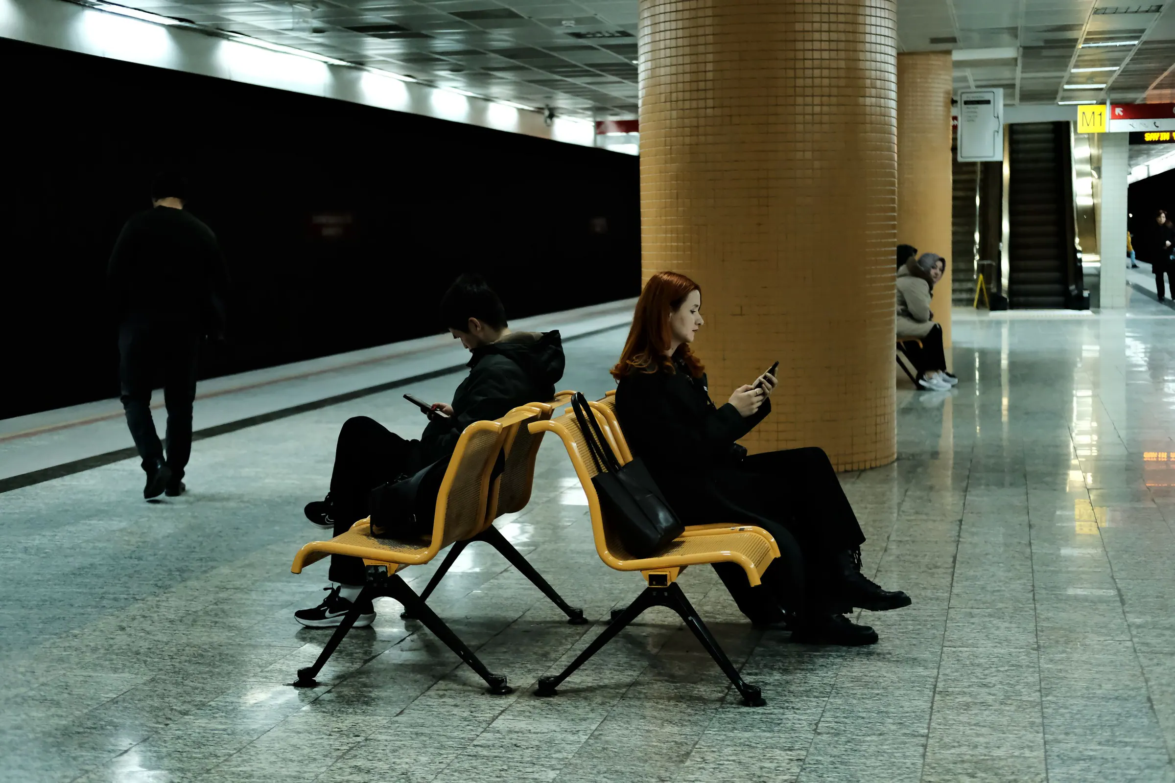 Travelers using smartphones while waiting in a metro station