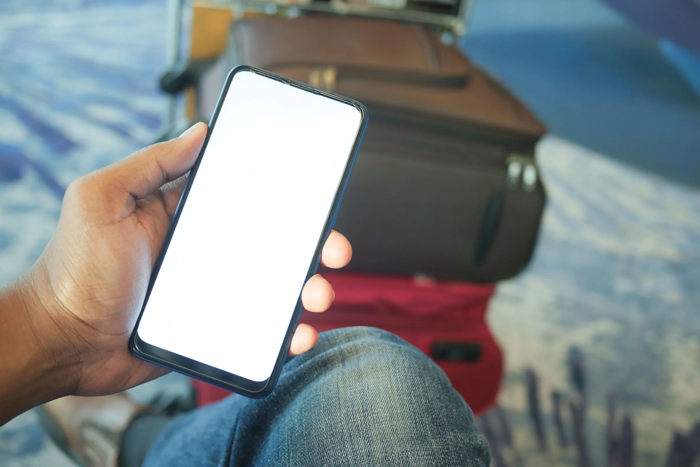 Traveler checking a smartphone beside luggage before leaving an airport