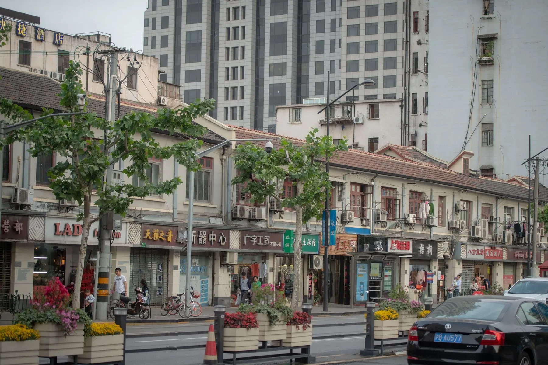 Pedestrians on a Shanghai street framed by traditional shops and modern towers