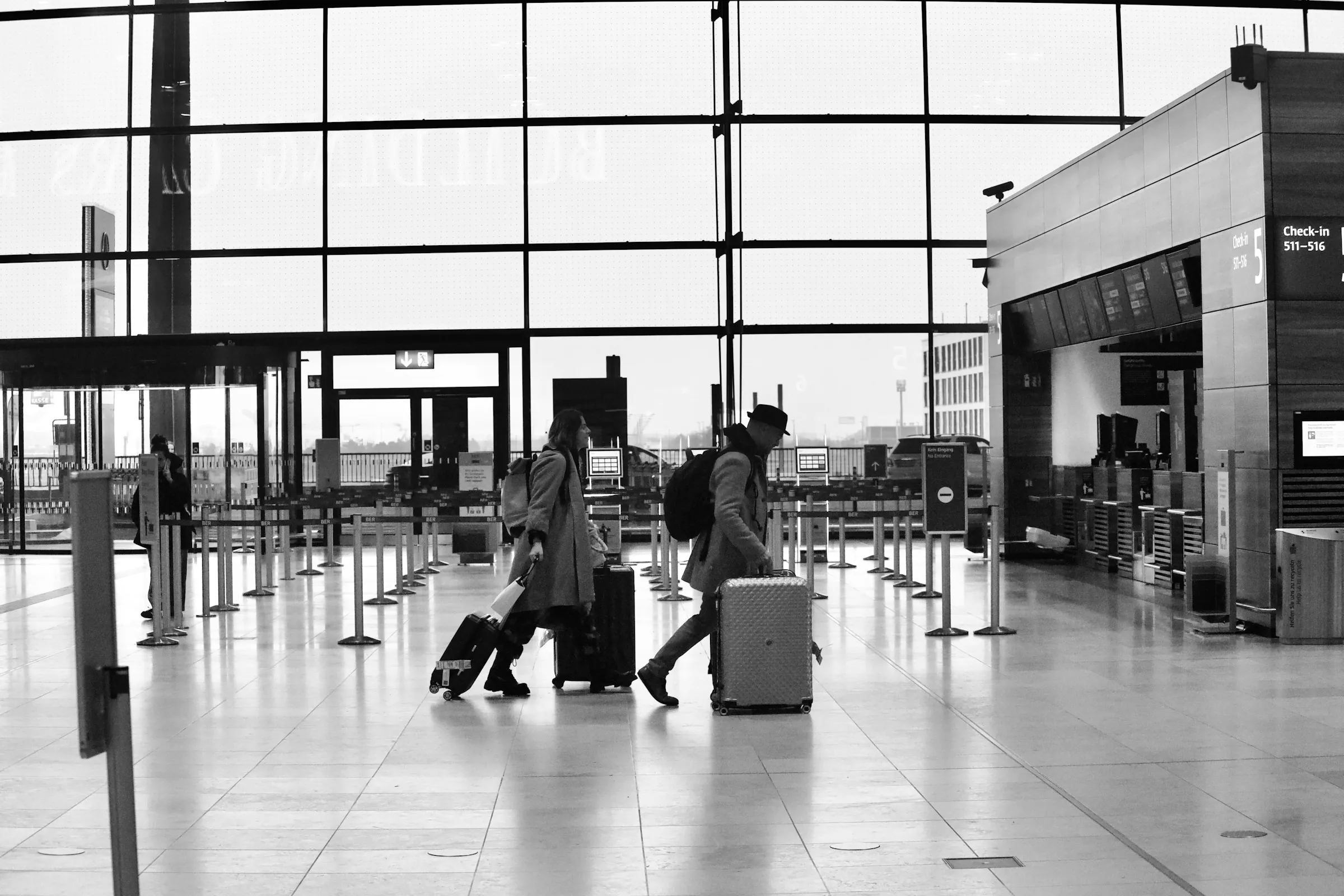 Travelers pulling luggage through a modern airport departure hall